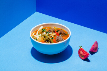 Traditional Asian, Uzbek, Middle East soup with beef or lamb and vegetables. Shorpa, sherpa, chorba on blue