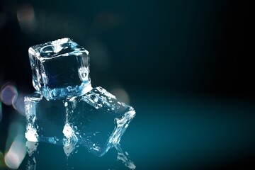 Natural ice cubes, melting on a dark reflective surface.