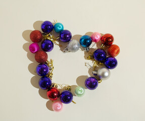 A heart silhouette made of shiny baubles on a beige background. Frame design. Minimalist concept of love. Flat lay. Copy space.