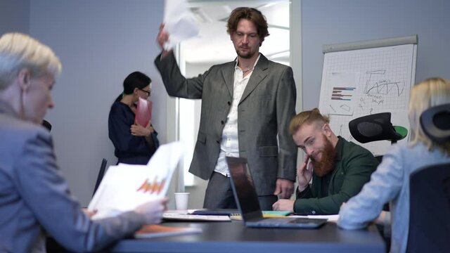 Portrait Of Angry Boss Firing Unproductive Manager At Business Meeting In Office. Dissatisfied Caucasian Serious Man Pointing At Door And Young African American Employee Leaving. Big Business Stress