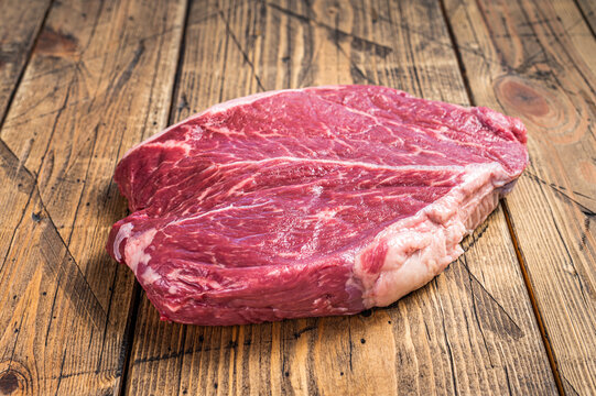 Dry Aged Raw Beef Round Steak Cut On A Butcher Table. Wooden Background. Top View