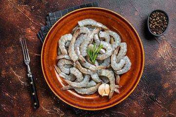 Black Raw uncooked Headless giant shrimps prawns in a rustic plate. Dark background. Top view - obrazy, fototapety, plakaty