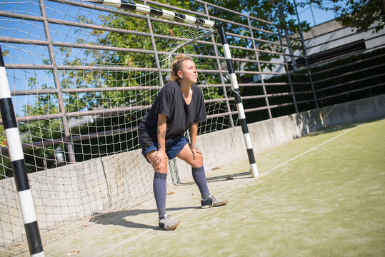 Attentive female goalkeeper standing in goals. Sportswoman in dark uniform getting ready to catch ball. Sport, leisure, active lifestyle concept