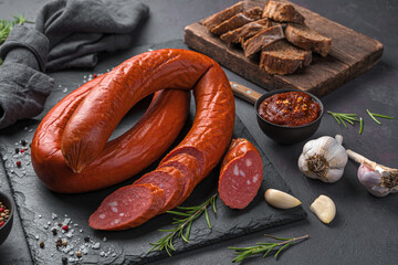 Krakow sausage with garlic and fresh rosemary on a dark background.