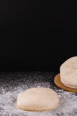 bread concept a few bun doughs with flour being in the middle on the black background