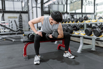 exercise concept The sport man picking up the dumbbell with his left hand while another dumbbell on...