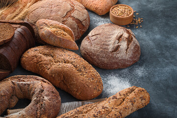 Assortment of rye and wheat bread on a dark background with flour.
