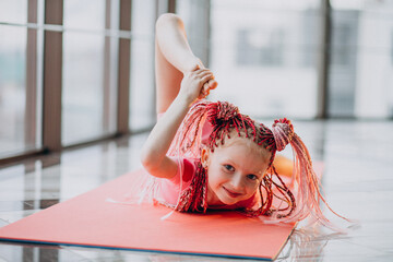 Cute little girl doing gymnastics on mat in studio - obrazy, fototapety, plakaty