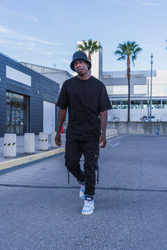 Vertical Shot Of A Young Black Man In Street-style Clothes Confidently Walking Outdoors