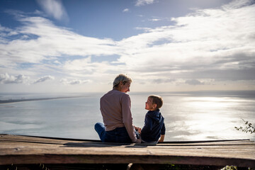 Mother and 3 years old son talking to each other having the beautiful ocean view, Portugal