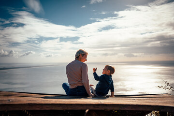 Mother and 3 years old son talking to each other having the beautiful ocean view.iew,