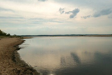 The coastal line of a sandy beach by the Baltic Sea on Sobieszewo island, Poland. The sea is gently waving. A bit of overcast. Solitude and serenity