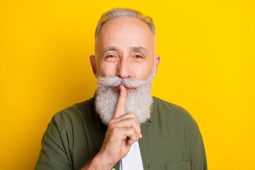 Photo portrait of elder man keeping finger near lips secret isolated vivid yellow color background