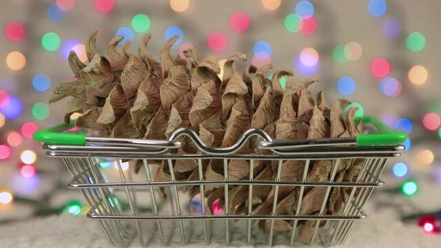Screensaver cedar cone in a basket against a background of Christmas lights. Copy space. Multicolored lights out of focus. Beautiful footage, video for intro, transition, intro. UHD 4K.