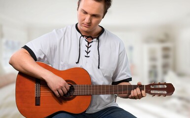 Obraz premium Lifestyle concept. Young musician playing guitar in the living room at home on this weekend.