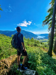 A man standing at a viewing point near the top of Oswaldiberg with the view on the Lake Ossiach in Austrian Alps, Carinthia. The hiker enjoys a panoramic view on the Ossiacher Tauern. Freedom