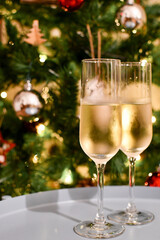 Two glasses of champagne with christmas tree background, christmas lights, bokeh lights effect