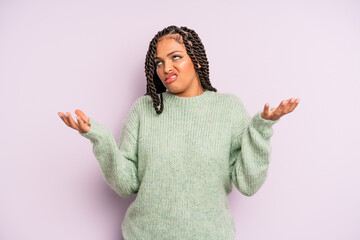 black afro woman shrugging with a dumb, crazy, confused, puzzled expression, feeling annoyed and...