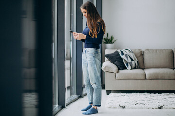 young woman typing phone keyboard by the window