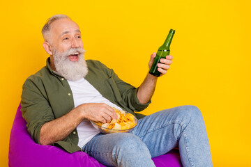 Photo of cheerful bearded man hold beer bottle chips bowl watch football wear green shirt isolated...