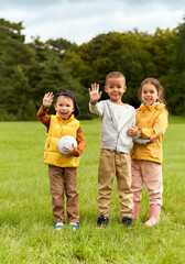 Fototapeta premium childhood, leisure and people concept - group of happy children with soccer ball waving hands at park
