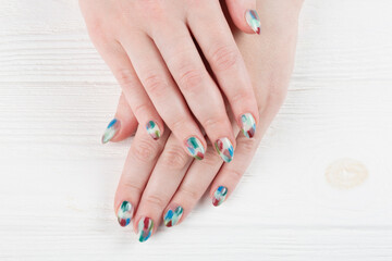 Female hands with stylish manicure closeup. Colorful nail art on wooden background.
