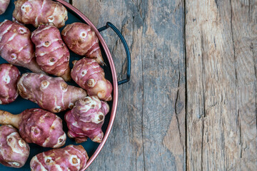 fresh ripe Jerusalem artichokes on wooden table with copy space