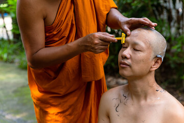 Asian man shaving his head by elder monk before ordain ceremony