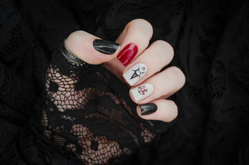 Black and red gothic manicure with mystic nail art. Creative nail concept on black lace background.