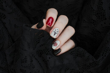 Black and red gothic manicure with mystic nail art. Creative nail concept on black lace background.