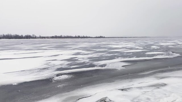 Snow river winter landscape. Frozen ice and snow by river. Spring thawed ice on water.