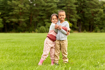 Fototapeta premium childhood, leisure and people concept - happy smiling little boy and girl hugging at park