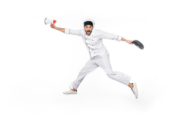 surprised young chef in hat and uniform levitating while holding frying pan and megaphone isolated on white.