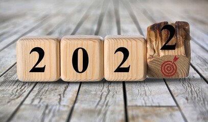 Business goals in 2022. Flips wooden cubes on a beautiful background. For starting business plan next year.