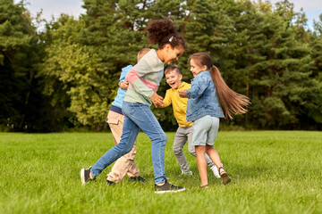 childhood, leisure and people concept - group of happy kids playing and having fun at park