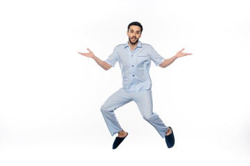 bearded man in pajamas levitating while gesturing on white.
