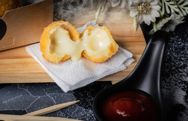 Yellow round fried food, stuffed with cheese, black background