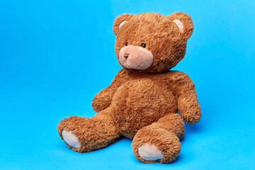 soft toys and childhood concept - brown teddy bear over blue background