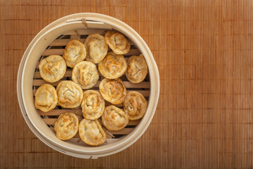 Fried dumplings in a double boiler on a bamboo mat. Asian street food. View from above. Copy space