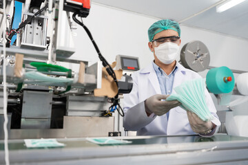 Fototapeta na wymiar male factory worker are producing medical face masks, counting and checking of quality from machine