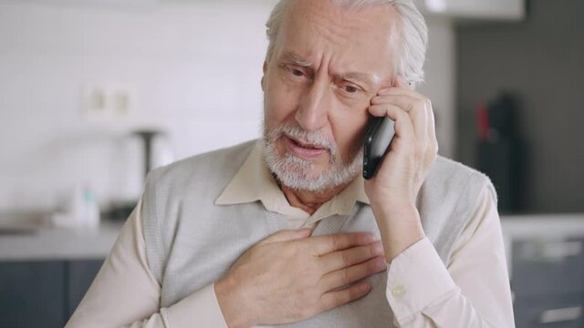 Senior man calling 911 ambulance, having chest pain, in need of medical aid