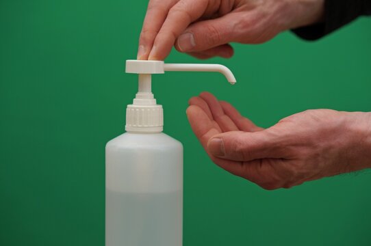 Closeup on hand sanitizer pump bottle on green screen background. Caucasian hands pumping bottle on screen screen.