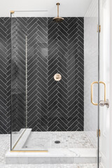 A black single herringbone tiled shower in a luxury home with gold hardware.