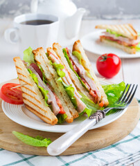 Sandwich for breakfast with stuffed tomatoes with ham and lettuce on a light wooden background. Selective focus.