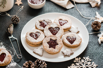 Ready Linzer cookies with berry jam on a plate on a dark background. Cooking Christmas treats. Lifestyle. Close-up