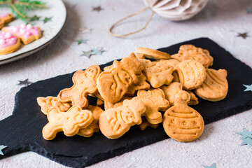 Freshly baked Christmas cookies are piled on a slate on a decorated table. Festive treat. Close-up