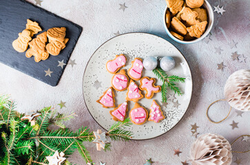 Freshly baked Christmas cookies with pink icing on a plate on a decorated table. Festive treat. Top view.