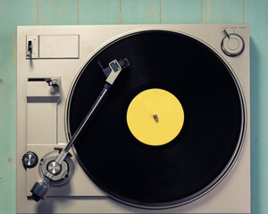 Gramophone with a vinyl record on wooden table, top view and copy space,photo desaturate and split toning for old style.