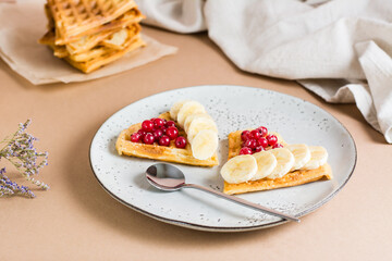 Heart shaped Belgian waffles with red berries and banana on a plate on the table. Valentine's Day