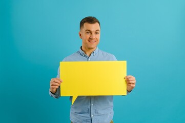 guy holding speech bubble on blue studio background, mockup for design